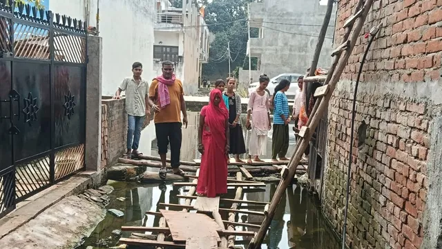 बनारस में मंत्री हंसराज विश्वकर्मा के वार्ड की गली में लकड़ी का पुल बना सहारा, तीन महीने से जलभराव से परेशान लोग